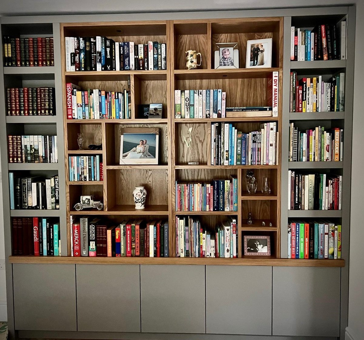 Painted bookcase by John Ladbury with touch-to-open cupboard doors and oak wood inserts. #johnladbury #notjustkitchens #bespokefurniture #hertfordkitchens #handmadefurniture #designerfurniture #beautifulhomes #bookcase #bespokebookshelves #bespokebookcase