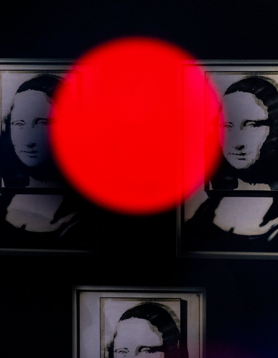 Replicas of Banksy's Mona Lisa are seen behind a red television camera light at a press conference announcing the return of 'The Art of Banksy' exhibit to Toronto in May.