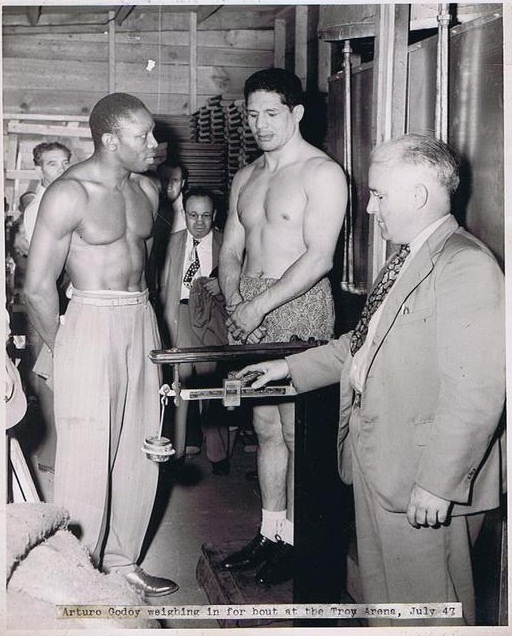 Cyclone Williams and former world title challenger Arturo Godoy weigh in for their rematch in Troy, New York in 1947. Godoy had won the first tilt by split decision but he stretched Cyclone in the return and got the knockout in round five. #Heavyweight #History #Boxing