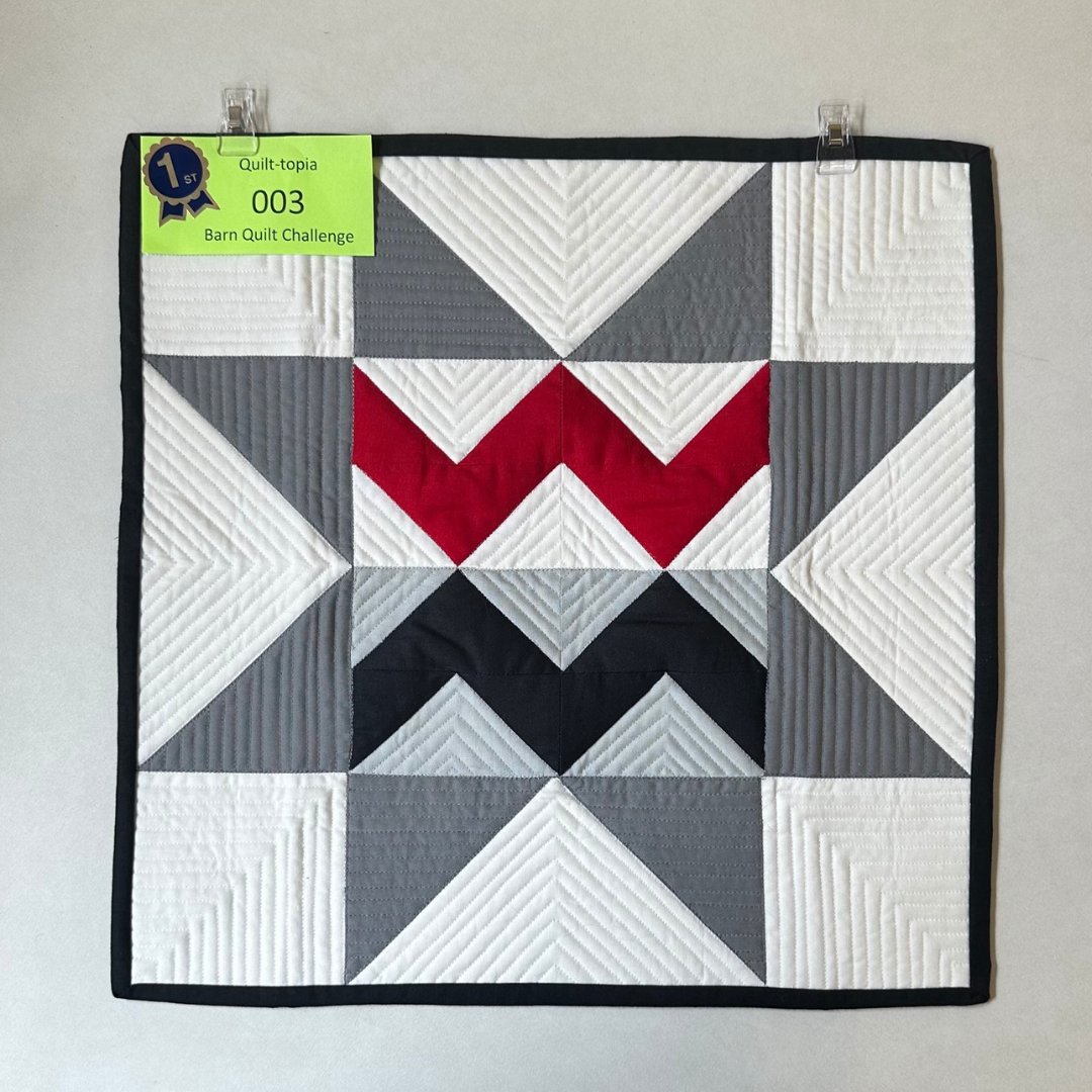 Congratulations to the 2024 Quilt-topia Barn Quilt Square Challenge winner, Jill Sauld from Washburn, Wisconsin. The strong graphic elements on a field of white and gray make the red “W” stand out as the focal point of this prize-winning quilt square.