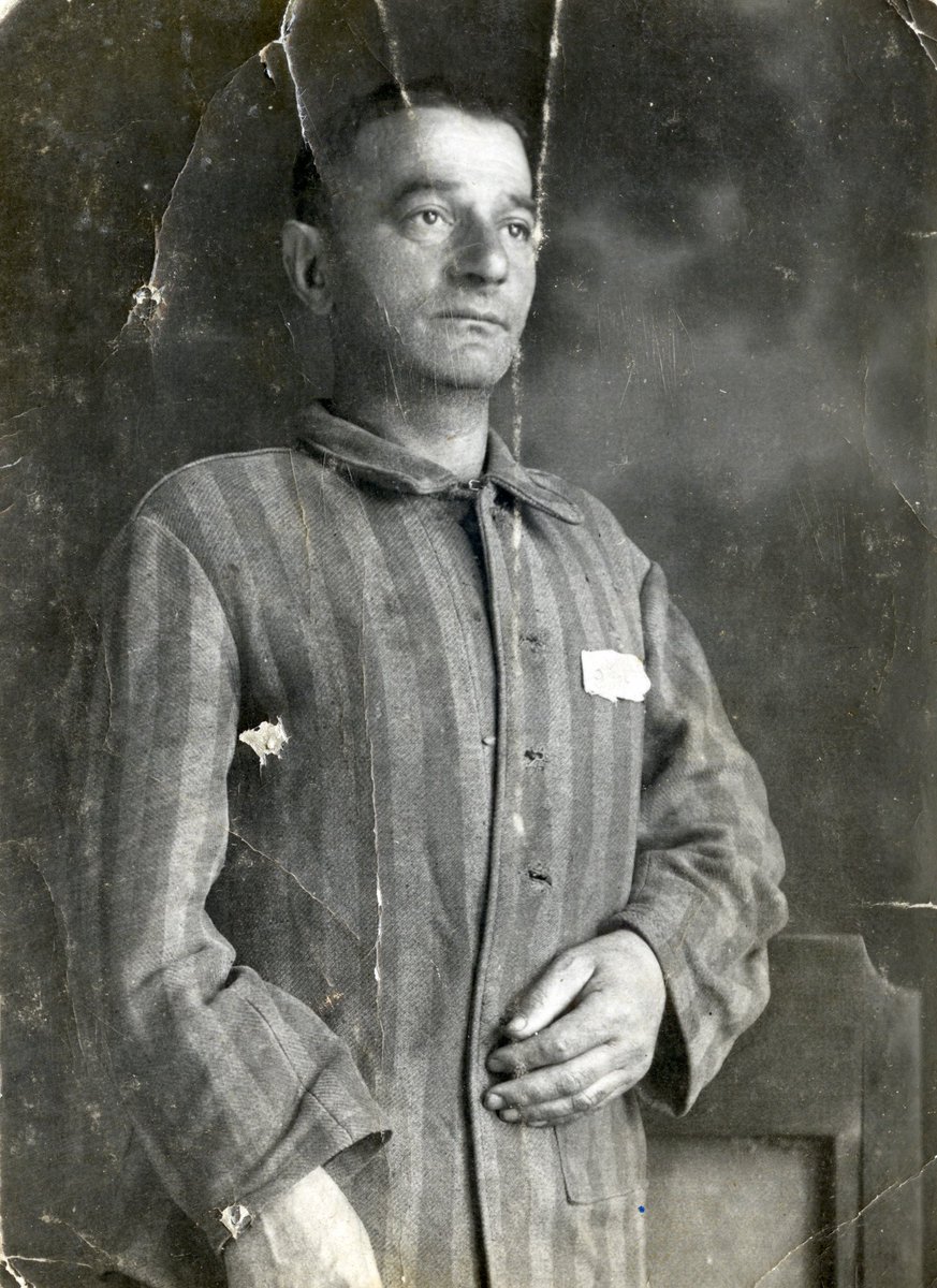 A portrait of defiance, Yaakov Michles posed for this photo in his prisoner uniform after being liberated from Dachau. The Nazis killed much of his family in the Holocaust. Dachau, created in March 1933, was the first regular concentration camp established by the Nazis.