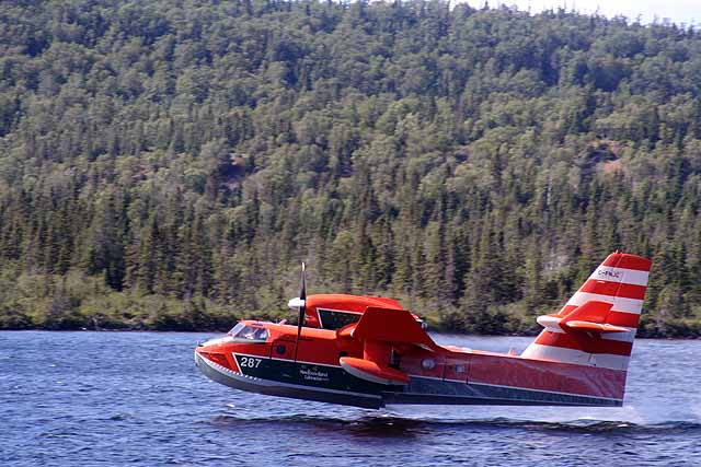 NL  water bomber CL415 lifts off a pond with her tanks full. The AMEs at their maintenance facility at Gander will  soon be preparing their fleet for another anticipated active forest fire season.