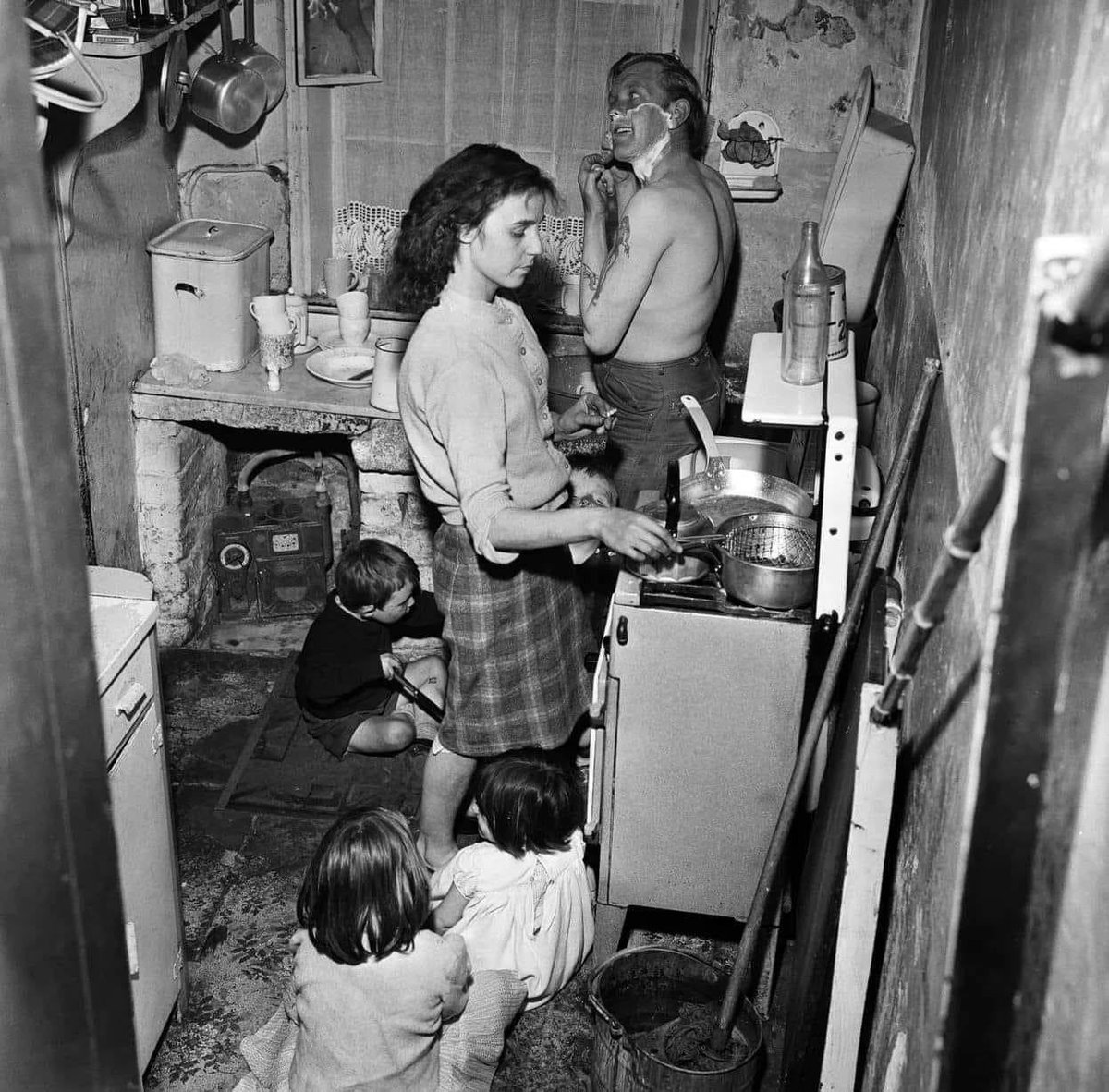 A photograph of Mr Sutton Pownall, a gravedigger, with his wife Joyce and their five children in a 150 year old house at Number Two Court, Dickenson Street, Oldham. Taken on the 1st June in 1962