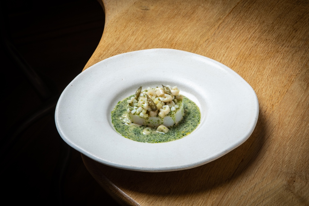 Steamed cod surrounded by a razor clam and fermented gooseberry sauce with diced cornichons, confit Jerusalem artichokes, wild garlic buds, chopped samphire, squid and razor clams running through it to complete our cod course.