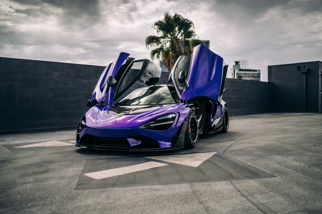 Purple McLaren 720S supercar with butterfly doors open in a parking lot.