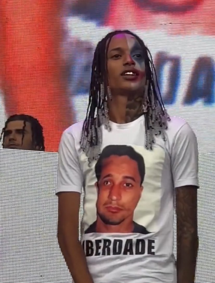 baudorio's tweet photo. ⚠️VEJA: Durante show no Lollapalooza, o cantor Oruam usou uma camisa pedindo liberdade para o seu pai Marcinho PV, apontado como liderança máxima da facção Comando Vermelho que está preso desde 1996. https://t.co/1qG9zE2RKv