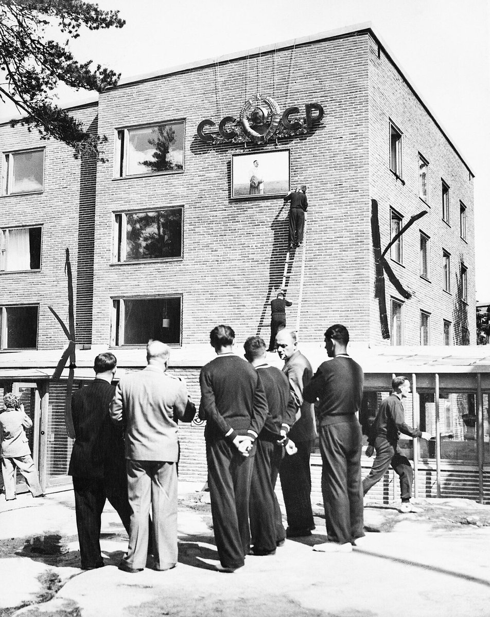 Members of the Soviet Olympic team place a portrait of Marshal Stalin beneath the hammer and sickle motif on the wall of the building where Soviet athletes are quartered at Otaniemi, Helsinki, 1952