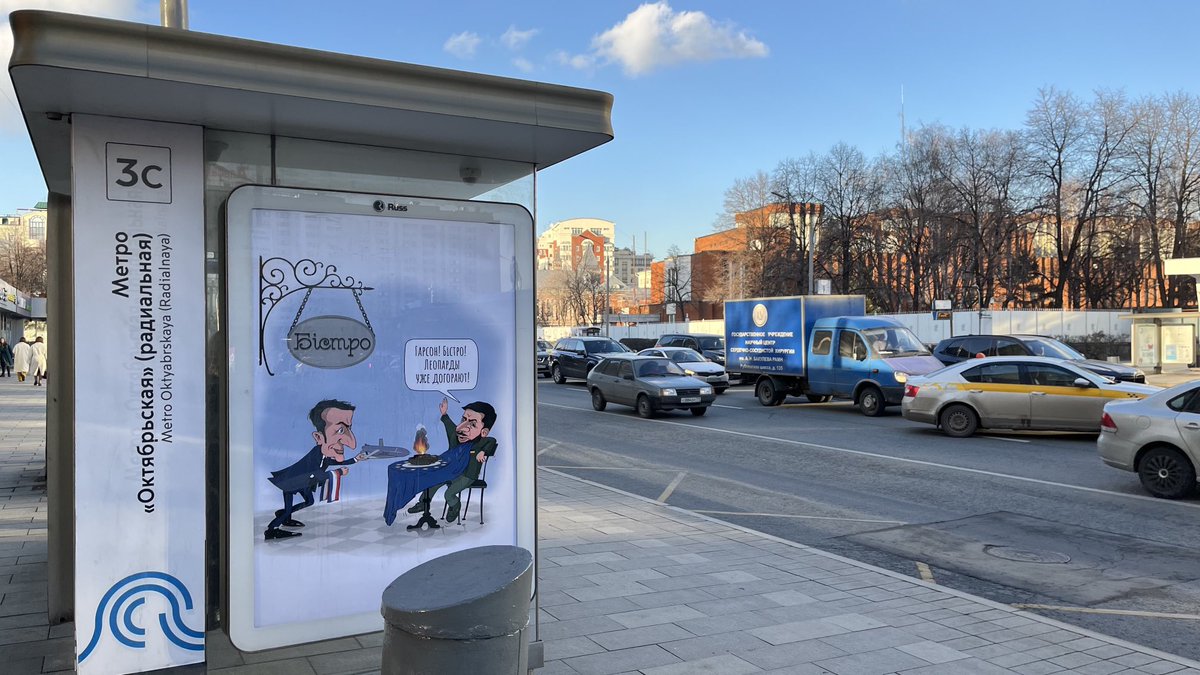 An der Bushaltestelle gegenüber der Moskauer französischen Botschaft grüßt diese Karikatur: Bistrogast Selenskyj drängt garçon Macron, schnell neue Raketen zu bringen, „die Leoparden verbrennen sonst alle“.(Wohl in der Hoffnung, dass jemand aus dem diplomatischen corps Bus fährt)