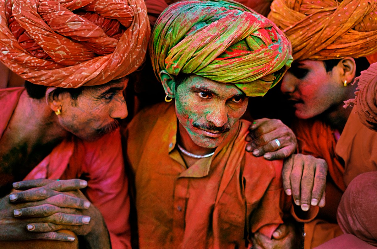 In the midst of the riotous sound and colour of the Holi festival, three men covered in powder are caught in conversation. Rajasthan, India, 1996.