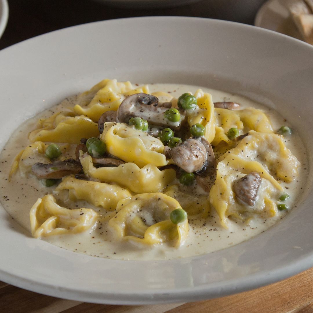 Handcrafted pasta parcels, generously filled with chicken and prosciutto served with mushroom and peas in alfredo sauce. Tortellini Gina, everyone! #italian #italianamerican #italianfood #KC #KCMO #kansascity