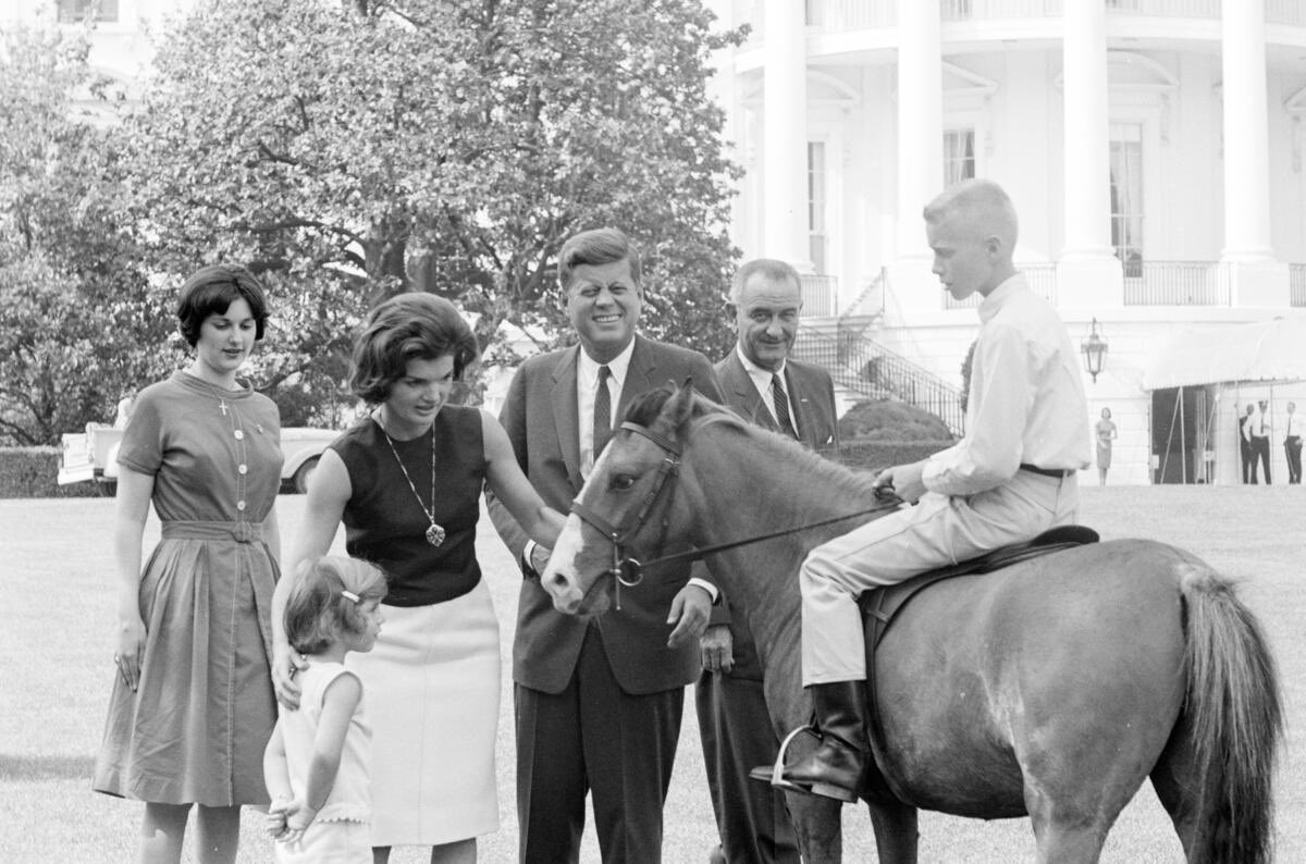 First Lady Jacqueline Kennedy and Caroline Kennedy visit with Tex, a pony given to Caroline as a gift from Vice President Lyndon B. Johnson; President John F. Kennedy, Vice President Johnson, and Lynda Bird Johnson observe. South Lawn, White House, Washington, D.C. 17th May 1962.