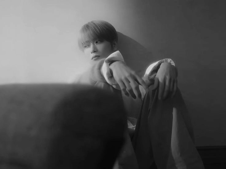 With his face downturned, shrouded in the shadows of his own contemplation, there lies an undeniable depth of emotion that speaks volumes of his inner turmoil. The quietude that surrounds him is not just an absence of noise, but a resonant echo of his thoughts, a silent symphony.