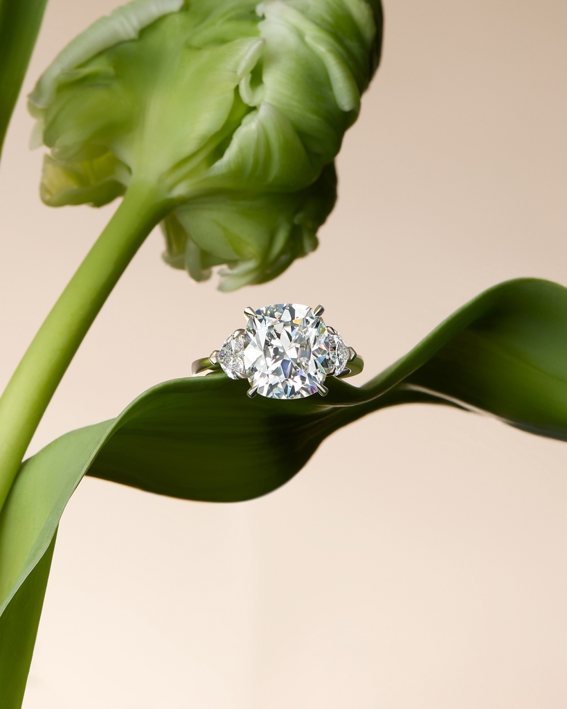 Petals bloom, diamonds loom. This extraordinary ring features a show stopping cushion cut diamond of over five carats, embraced by two heart shaped diamonds creating the perfect love story.⁠ #Boodles #Engagement⁠ #PeaceofMined ⁠