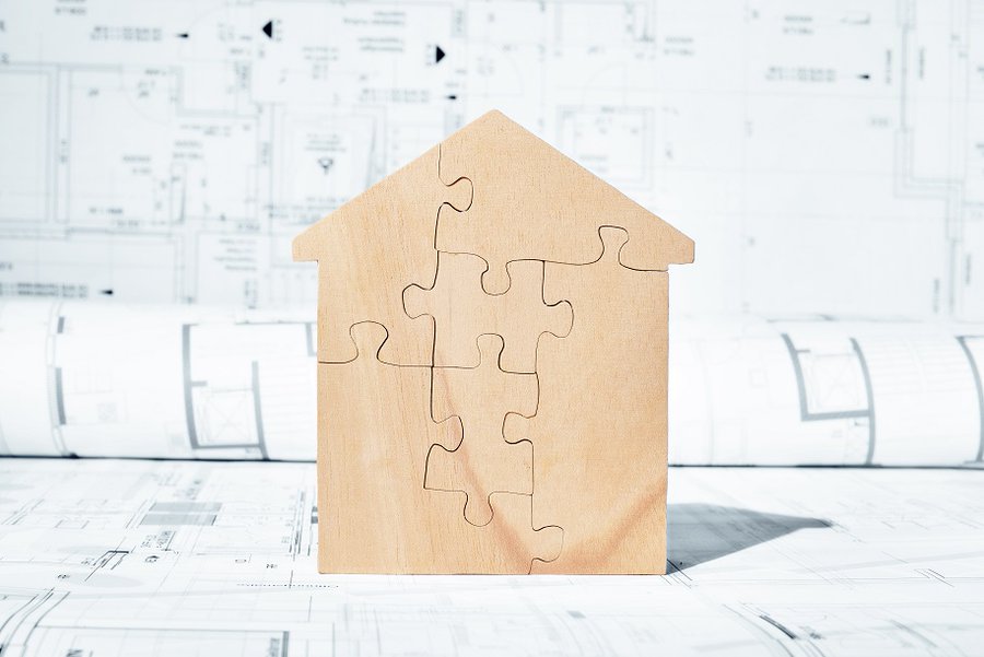 Wooden puzzle forming a house, placed on a land register plan