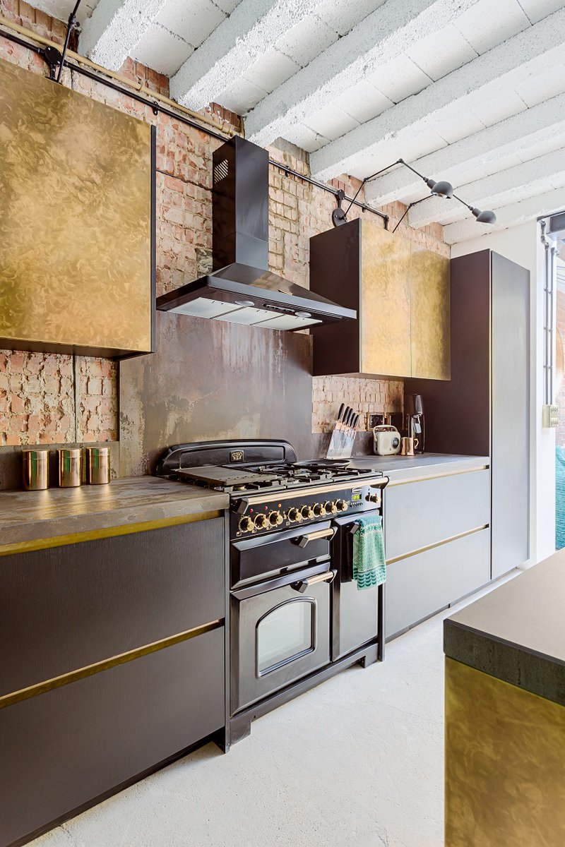 With exposed bricks, concrete floors, and ceilings, the loft style of this luxurious kitchen is enhanced with an antique-treated brass island and wall units combined with black ultra-matt laminate doors. #metallickitchens #scandihome #homeinspo l8r.it/xo4m