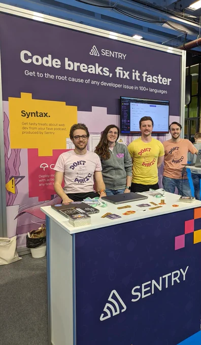 Four people in Sentry swag at a Sentry branded booth at a conference.