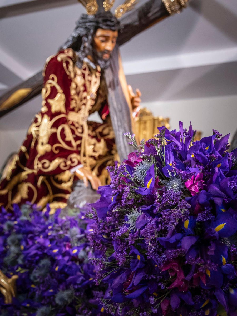 El paso de misterio del Santísimo Cristo de las Tres Caídas se presenta con un exorno floral de una armonía monocromática con diferentes intensidades de morados, compuesto por iris morados, alelí malva, fresias moradas, eringiym, limonium, hiedra, romero y esparraguera.