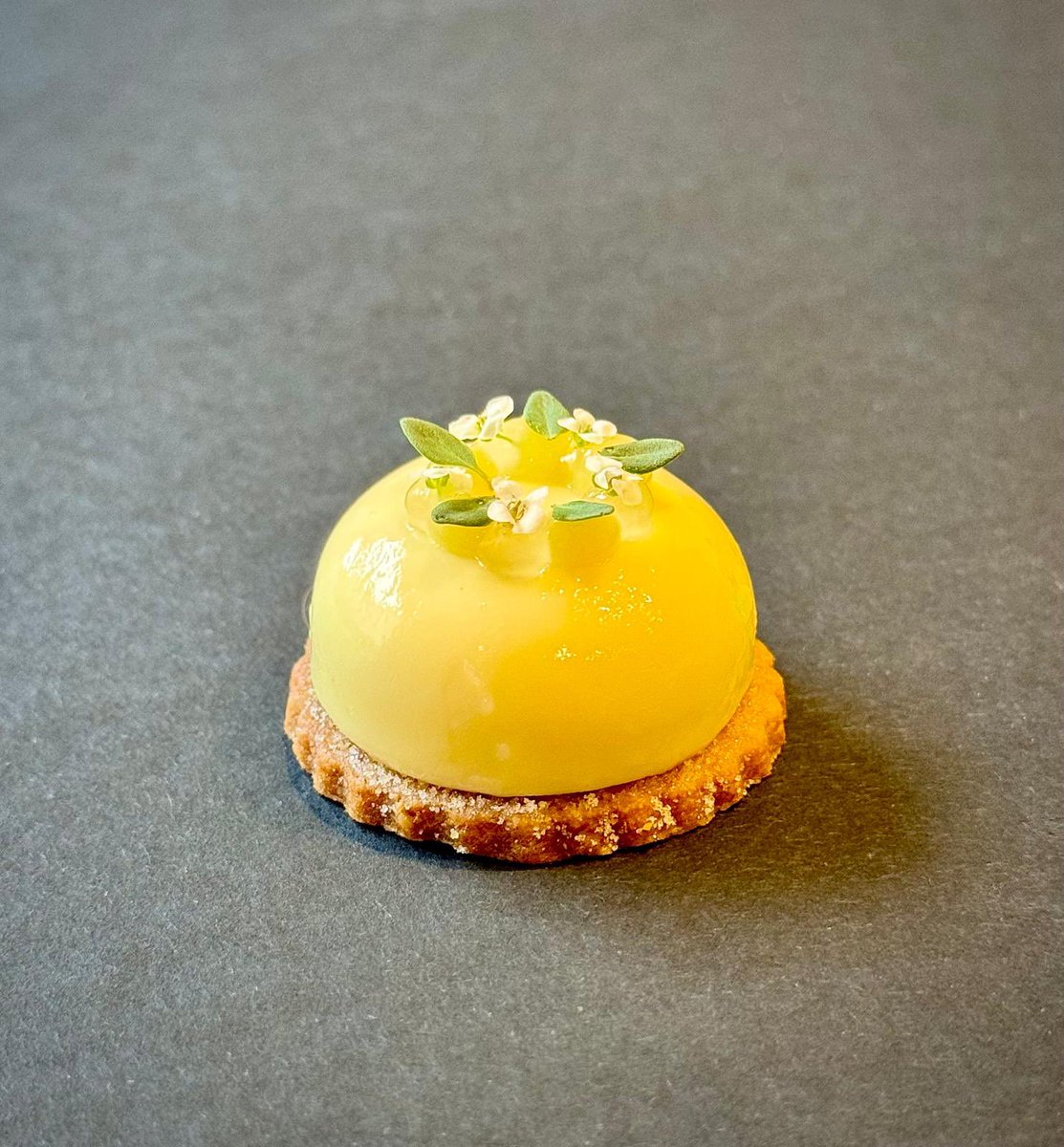 AMALFI LEMON Lemon & lemon thyme bavarois made from the zest & the leaves of the Amalfi lemons The bavarois is then dipped in a lemon glaze & sat on a sweet sable biscuit which has been dusted with a lemon sherbet Topped with lemon gel, lemon curd, white alyssums & lemon thyme