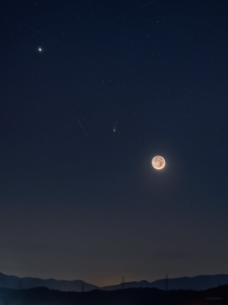 春宵に並んだ月と彗星と木星。 二日月の陰の部分の地球照が、肉眼で見るよりも明るく満月のように写っています。 左上の明るい星が木星。 写真中央の小さく尾を引いた天体が彗星です。 いくつか細い線のように写っているのは人工衛星の軌跡です。 （昨日、山形県にて撮影）