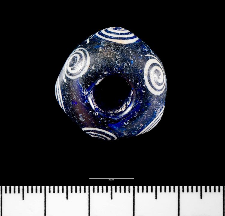 A beautiful display of native #IronAge craftswork - this vivid royal blue glass bead with white spiral design is probably from a necklace. Discovered in a rubbish heap at Glanbidno Uchaf, Llangurig, it's now part of the collection at Amgueddfa Cymru 📷Copyright Amgueddfa Cymru