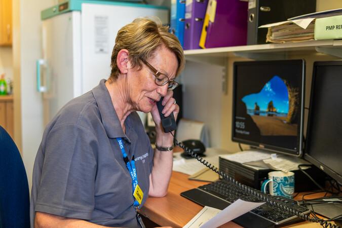 The below is a photo of a hospital volunteer. ❓Based on what she's doing, which current healthcare challenge do you think this helps the @NHS address: - Patient flow? - DNAs (Did Not Attends)? - Healthcare Recruitment? @MrsBosanquet @AVMtweets @jojohowarth @emmaeaston12