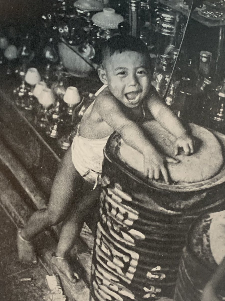 Kid in a lights and lanterns store, Singapore, 1937