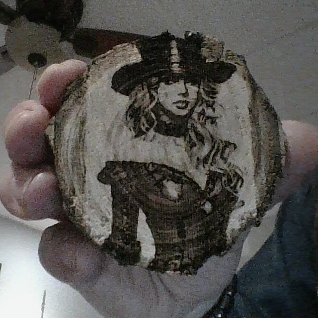 An engraving of one of my characters on a slice of a tree branch.