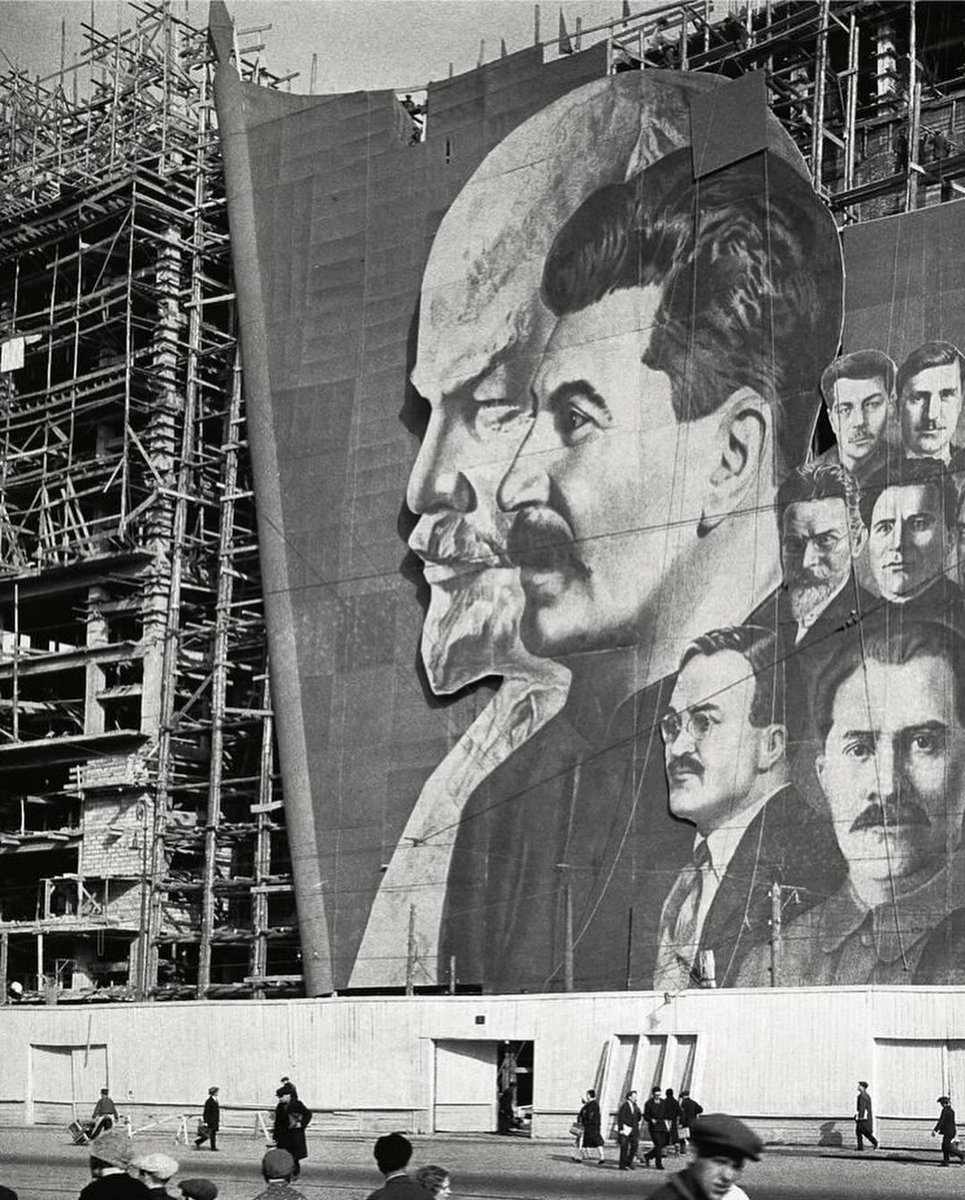 Decorations with portraits of Vladimir Lenin and Joseph Stalin for the May Day parade hang on the scaffolding of a building under construction, Moscow, USSR, 1934.