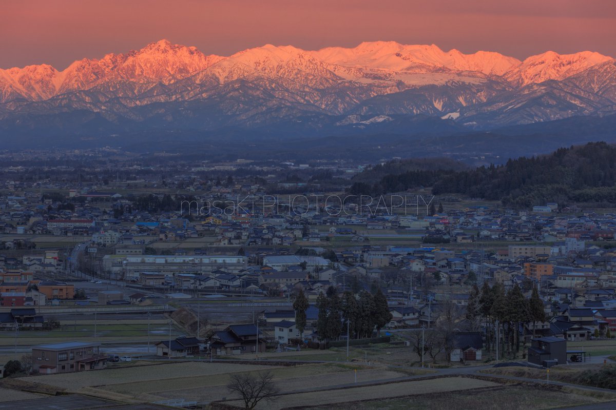 夕暮れ時の立山連峰。 茜色に輝く山々と夜色に染まる平野とのコントラストが印象的です。 写真は先々週、富山市から撮影。