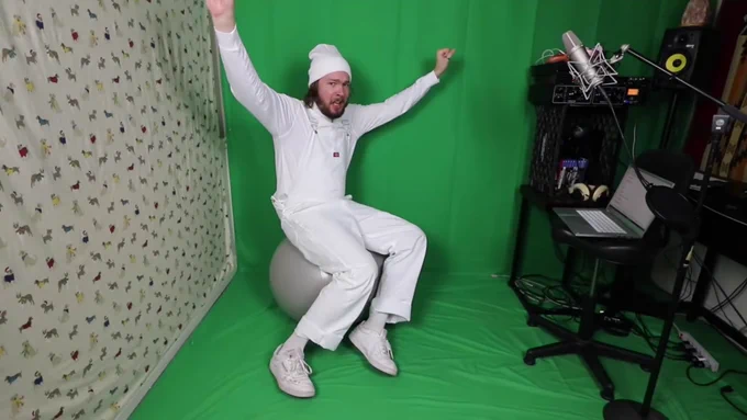 NakeyJakey on his exercise ball in front of a green screen 