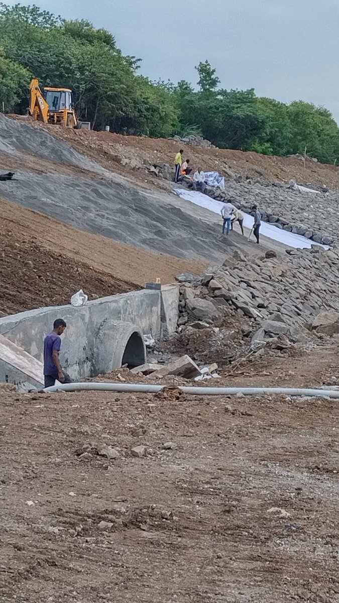 Covered by geo textile+rocks was once covered by greenery as in background. Concrete storm drain is going to pour storm water+solid waste debris+sewage, etc. into channelised river. This is 'river rejuvenation'? @PmcPuneRe? @PMCPune? P.C.: Shailaja Deshpande (context: ALT text)