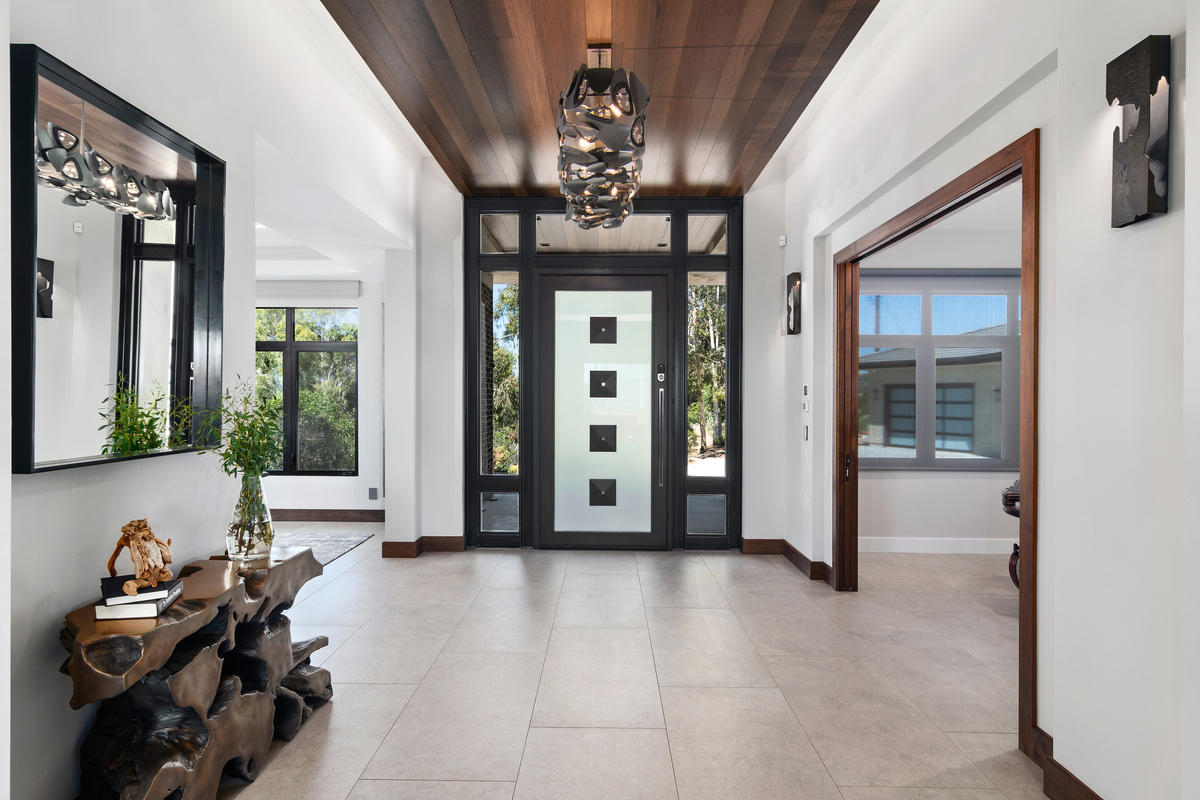 A drop down ceiling with a floating effect and a stunning sculptural light fixture define the entryway for this mountain top retreat.