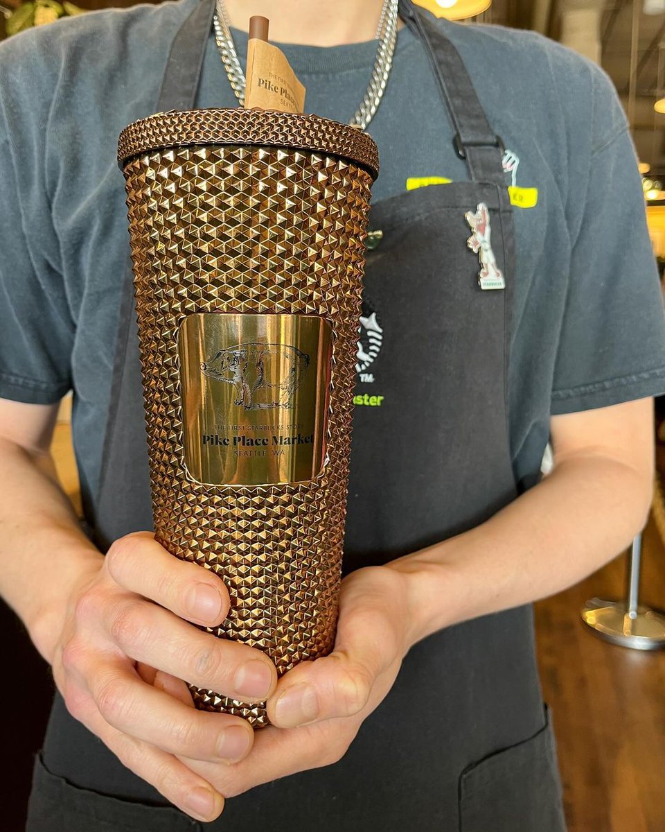 Get this exclusive studded cup only at #PikePlaceMarket! ✨ This shimmery bronze 24 oz cup features Rachel the piggy bank. The best part: $2 from every cup purchase goes to the @MktFoundation.🐖💚 Only find this mug at the first Starbucks in Pike Place Market!