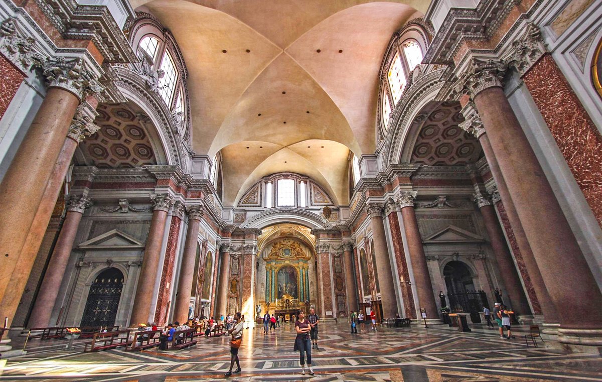 OptimoPrincipi's tweet photo. The enormous frigidarium of the Baths of Diocletian in Rome, built around 300 AD – repurposed by Michelangelo in 1563 into the Basilica of St. Mary of the Angels and the Martyrs, though retaining many of its ancient red granite columns and pilasters. A rare glimpse at the scale and majesty of a Roman imperial bathhouse. 
Michelangelo actually had to raise the ancient floor by three metres to match the level of the sixteenth-century streets and protect against rising moisture, so the original ancient space was even greater still; about fourteen metres of the seventeen-metre columns are visible today, their original Roman bases hidden under the basilica floor and which Michelangelo replaced by reproductions.