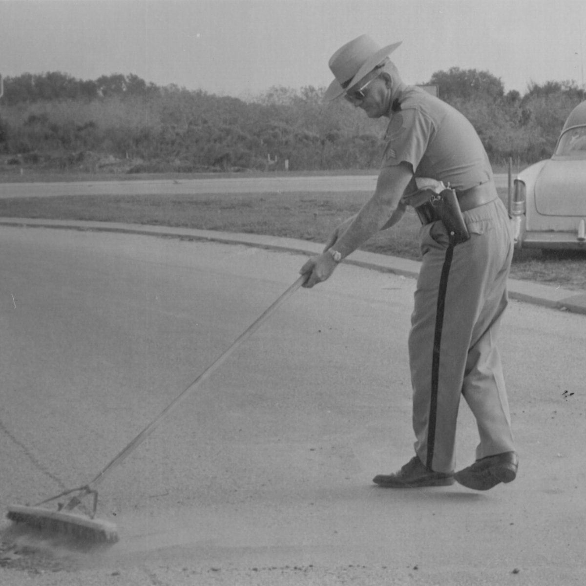 Sgt. G.W. 'Whitney' Knutsen clears the roadway from debris following a crash in Manatee County 1963. #FHP #StateTrooper #ThrowbackThursday #LawEnforcement #ManateeCounty #FloridaHistory #PoliceWork #VintagePolice #PoliceOfficer #1960s