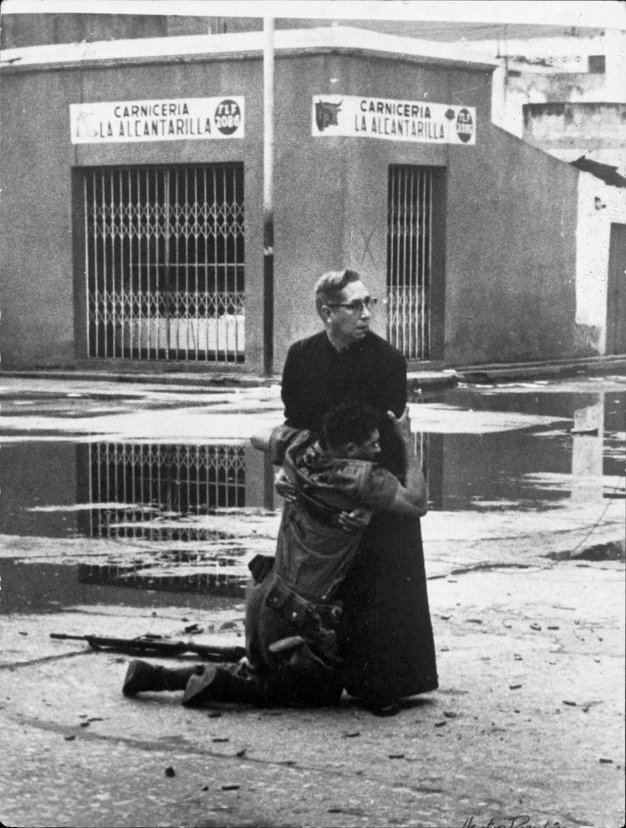 The iconic photograph captured by Hector Rondon Lovera in Venezuela in 1962 depicts Catholic priest Luis Padilla giving last rites to a soldier wounded by sniper fire during a revolt. This image won both the World Press Photo of the Year in 1962 and the 1963 Pulitzer Prize for…