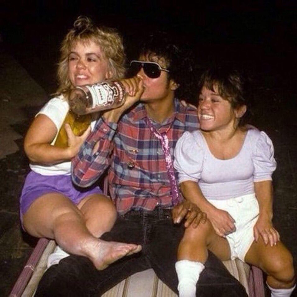 Michael Jackson drinking vodka in the company of two female dwarfs on the set of Captain EO, 1986.