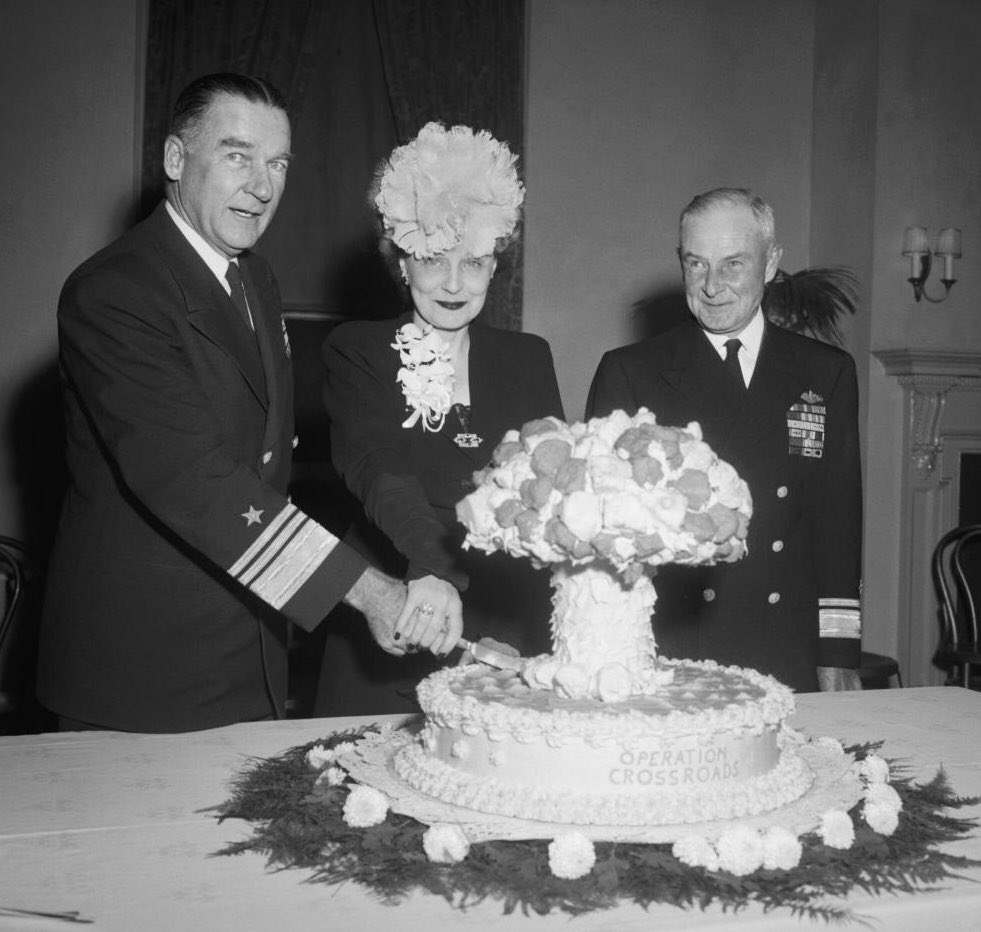 Apropos: Celebrating the Bomb: US Navy Vice Admiral William H. P. Blandy, his wife, and Rear Admiral Frank J. Lowry cut a cake made in the shape of a mushroom cloud formed by the explosion of an atom bomb at a reception for Operation Crossroads, a US program that tests nuclear…