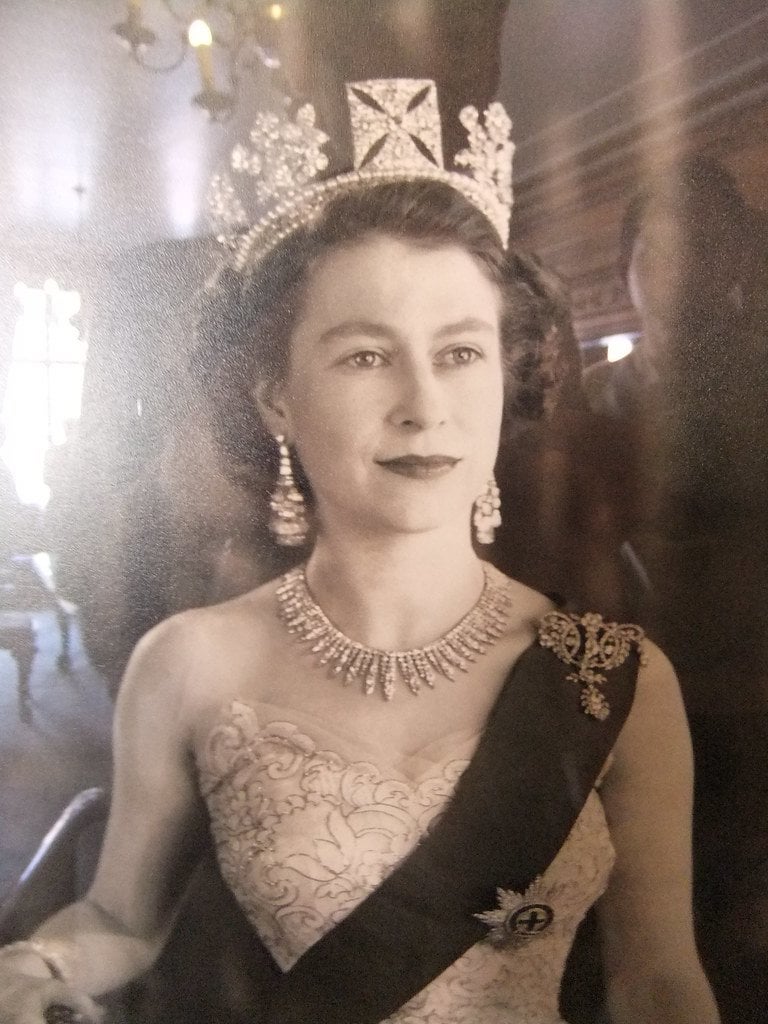 Polaroid photo of a young Queen taken inside Nottingham's Council House.

I got questions for what's going on with the left side of 'its' face to the right of the Queen. That's not human. Could the Polaroid have allowed for the creatures liquid crystal hologram to be disrupted?