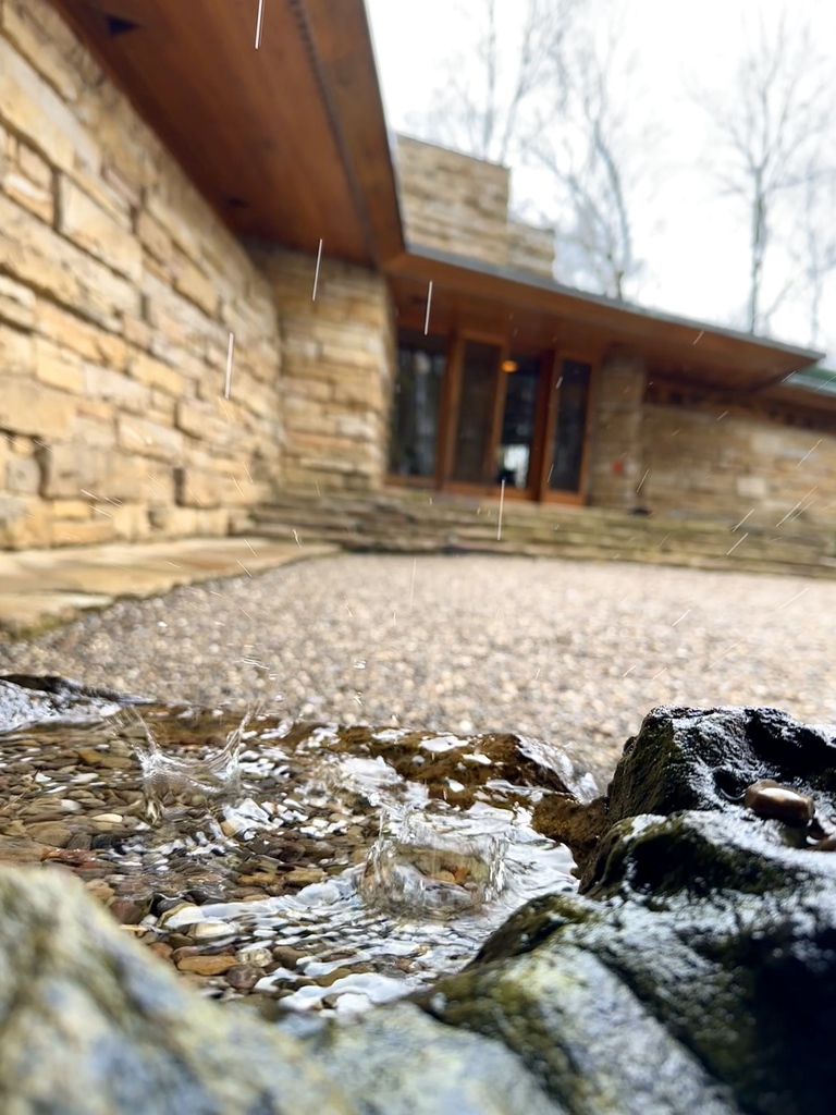 April rain showers are captured by the stone birdbath at the edge of the carport. — Explore the wonders of nature and the beautiful views surrounding Kentuck Knob. Tickets available at our website (link in bio).