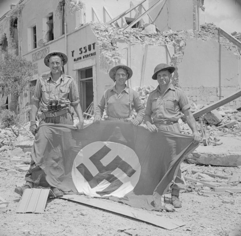 Men of the 1st Reconnaissance Regiment, part of the 1st Infantry Division, pose with a captured German swastika flag in Littoria, Italy, 25 May 1944.

They are, from left to right: Corporal H. Seddon, Trooper R. Carslake and Trooper J. Callaghan.

#britisharmy #Britishhistory…