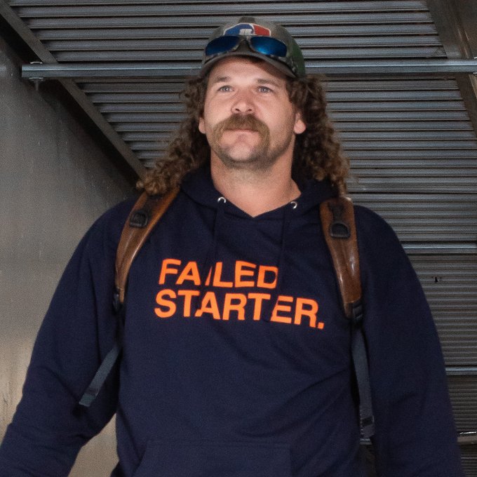 Andrew Chafin wearing a dark blue hoodie with orange letters that read "Failed Starter." He's wearing a hat with sunglasses resting on the brim.