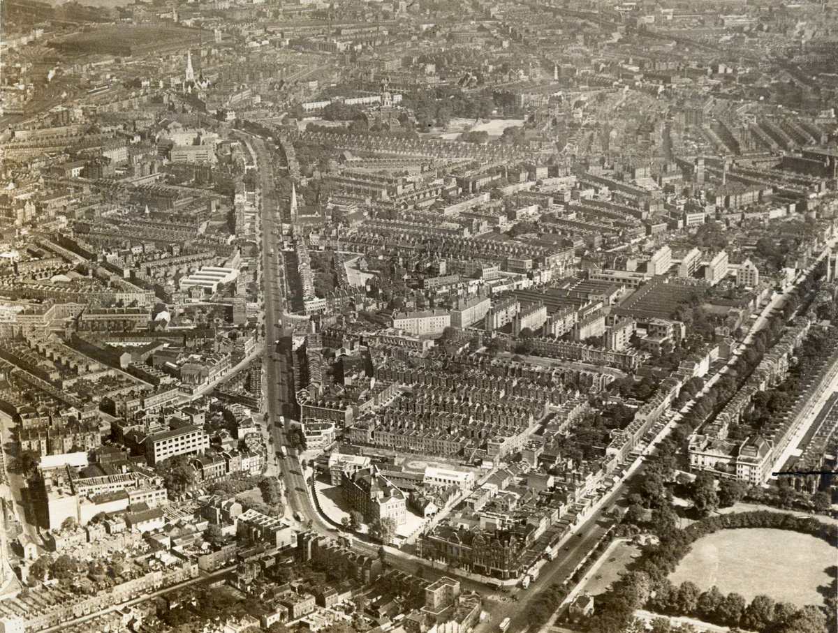 Aerial view looking north up Kennington Road towards Lambeth North. Kennington Park is lower right and The Horns Tavern opposite on the corner of Kennington Park Road. Kennington Theatre is above the park on the lower right. Photograph by Aero Films dated 1934