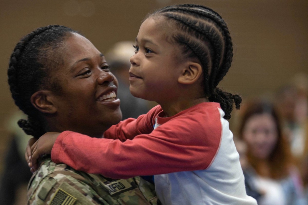 Army Staff Sgt. Erica Bradfield holds her child during a redeployment ceremony at Fort Stewart, Ga., Feb. 8, 2024. The event allows families to greet soldiers as soon as they get off the plane. (U.S. Army photo by Pfc. Rebeca Soria)
