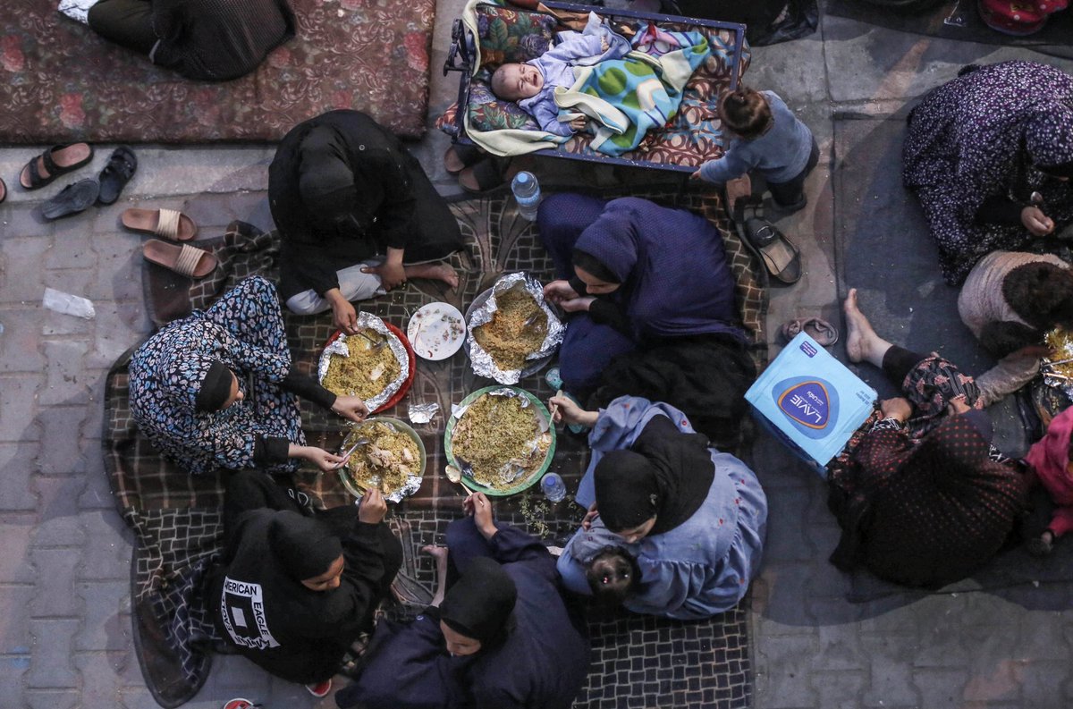 Palestinian families, displaced by Israeli attacks and finding refuge in a UNRWA school within Maghazi Refugee Camp, break their fast in the school's courtyard with meals distributed by well-wishers in Al Maghazi, Gaza on April 06, 2024. Photo by Ashraf Amra