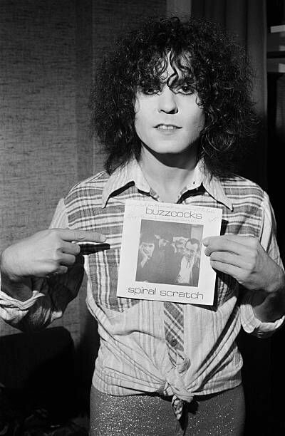 August 23rd 1977, Granada Studios, Manchester. Marc Bolan is in town to record his TV show 'Marc'. Photographer Kevin Cummins is on set & hands Bolan a copy of Buzzcocks classic 'Spiral Scratch' EP. Cummins also took the picture
