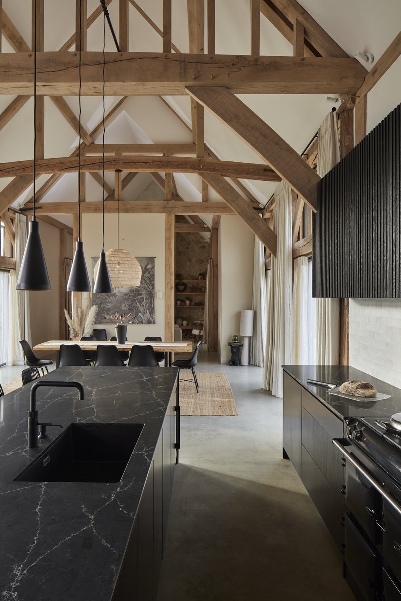 The subtle sheen of dark stone worktops set against the slim slats of the 'Skog' style wall units combined with flat oak-veneered cabinetry complements this impressive space with a minimalistic aesthetic! #scandikitchen #homeinspo #luxurykitchens l8r.it/n5Pf