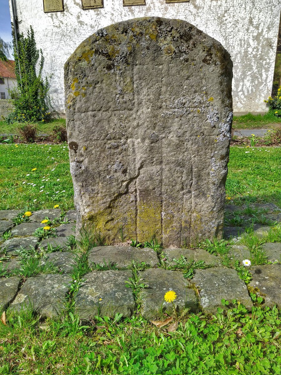 Der Kreuzstein Benstorf Lkr. Hameln-Pyrmont auf einem Thieplatz nahe der Kirche. Zu sehen ein Balkenkreuz und an der rechten unteren Seite weitere Linien, der Literatur nach Werkzeug oder Waffen