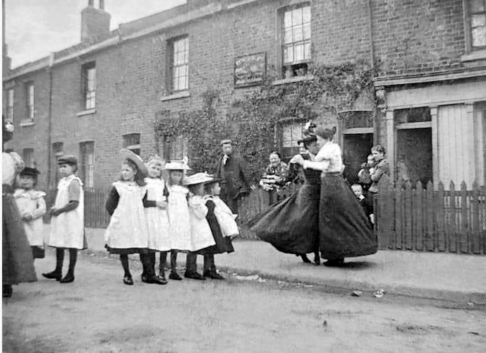A photograph of women and children Dancing in the street , taken at 
8 Smedley Street, Clapham, in 1905.