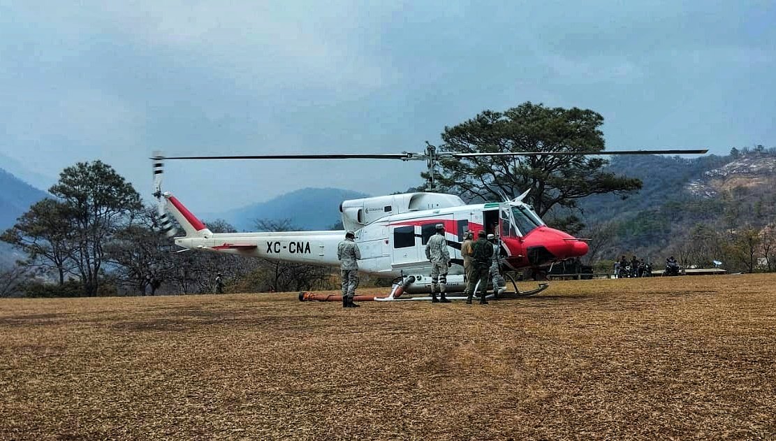 La #GuardiaNacional, en apoyo a las autoridades de protección civil de #Oaxaca, proporciona seguridad perimetral durante el aterrizaje de aeronaves que realizan descargas de agua a través de helibaldes para sofocar los incendios que registran en la entidad.